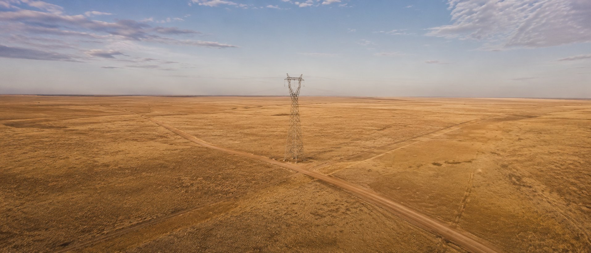 Aerial view of vast open American plains with transmission tower — infrastructure-ready land, national site selection by Artemis Commercial Group